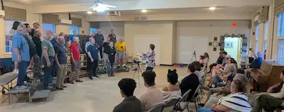 Chorus member teaching a young singer during outreach lesson